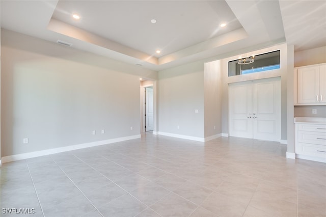 tiled empty room featuring a raised ceiling