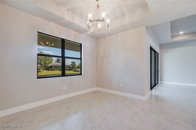 tiled empty room with a tray ceiling and a notable chandelier