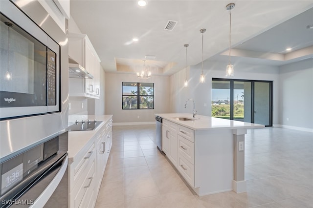 kitchen featuring a wealth of natural light, stainless steel appliances, white cabinetry, and a kitchen island with sink