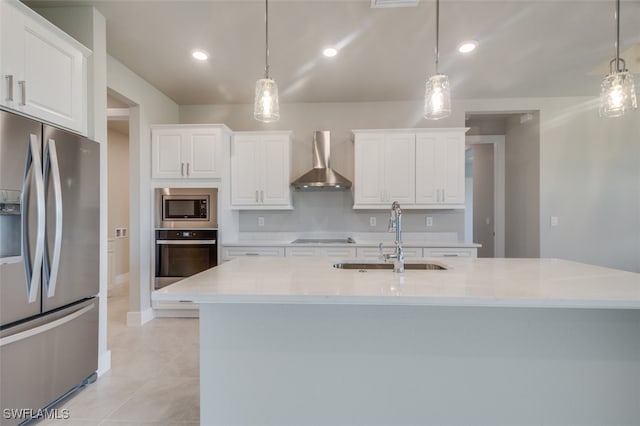 kitchen featuring pendant lighting, white cabinets, wall chimney range hood, sink, and appliances with stainless steel finishes