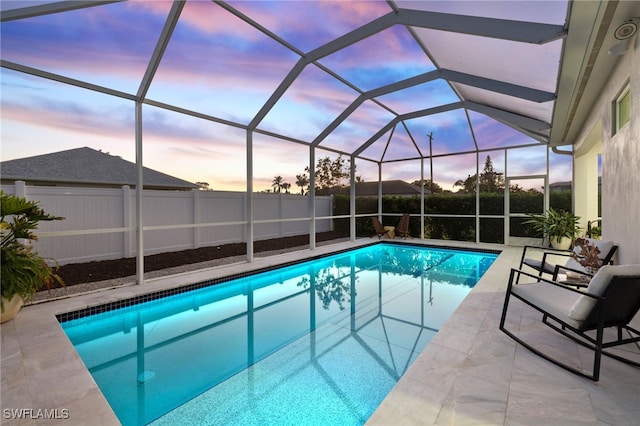 pool at dusk featuring a patio area and a lanai