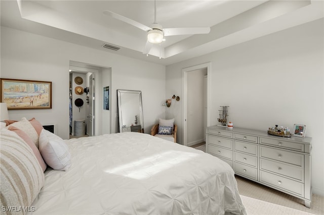 carpeted bedroom featuring a raised ceiling and ceiling fan