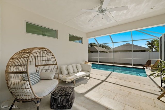 view of swimming pool with glass enclosure, ceiling fan, and a patio