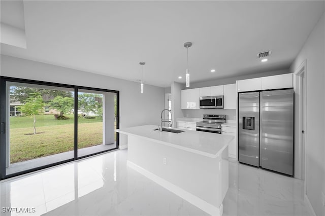 kitchen featuring stainless steel appliances, white cabinets, sink, an island with sink, and pendant lighting