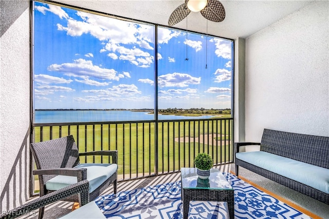 sunroom / solarium with a water view and ceiling fan