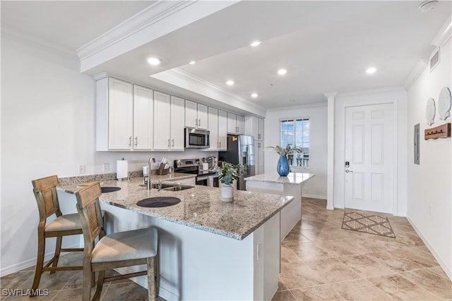 kitchen featuring white cabinetry, light stone counters, kitchen peninsula, a breakfast bar area, and appliances with stainless steel finishes