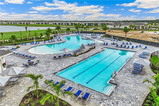 view of swimming pool with a patio area and a water view