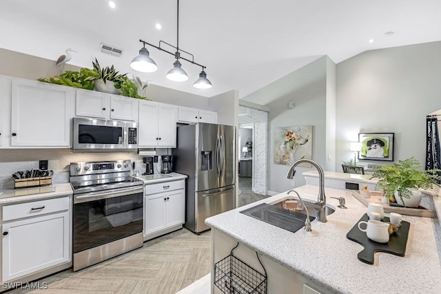 kitchen with appliances with stainless steel finishes, decorative light fixtures, white cabinetry, and sink