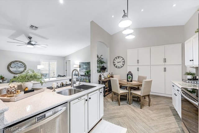 kitchen featuring sink, stainless steel appliances, pendant lighting, lofted ceiling, and white cabinets