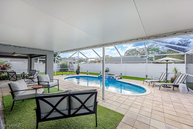 view of pool featuring glass enclosure, pool water feature, and a patio