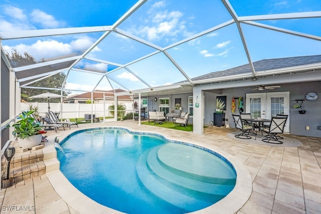 view of pool with pool water feature, a patio, glass enclosure, and ceiling fan