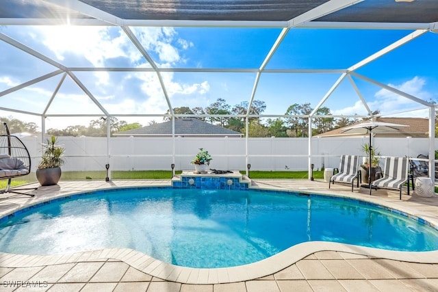 view of pool with a patio area, pool water feature, and glass enclosure