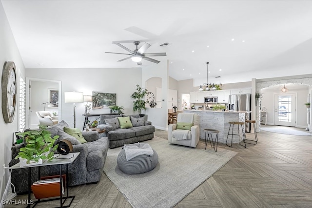 living room with ceiling fan with notable chandelier, light parquet flooring, and vaulted ceiling