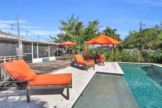 view of pool featuring a patio, a sunroom, and a deck