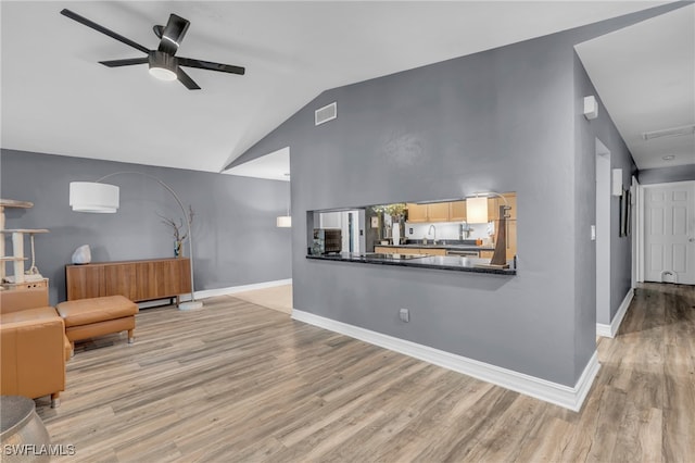 interior space featuring ceiling fan, sink, light hardwood / wood-style floors, and lofted ceiling