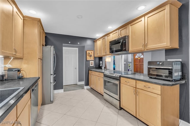 kitchen with sink, light brown cabinets, light tile patterned floors, and appliances with stainless steel finishes