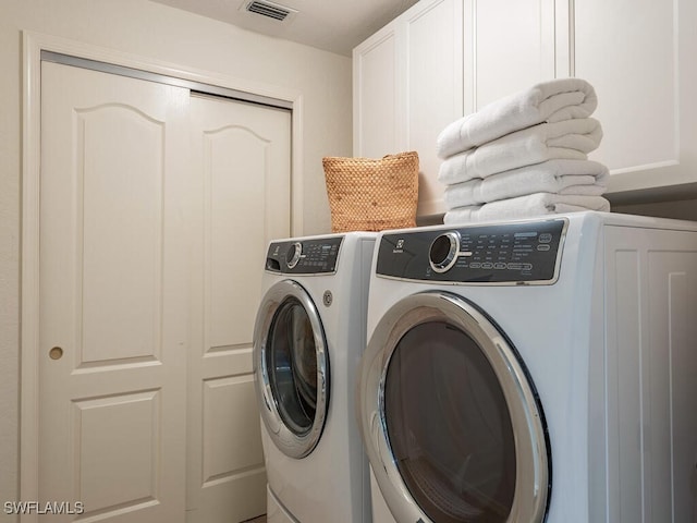 clothes washing area featuring washer and dryer and cabinets