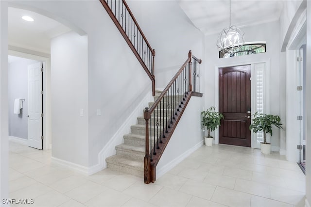 tiled entrance foyer featuring a high ceiling and an inviting chandelier