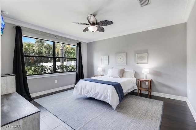 bedroom featuring ceiling fan, wood finished floors, visible vents, baseboards, and crown molding