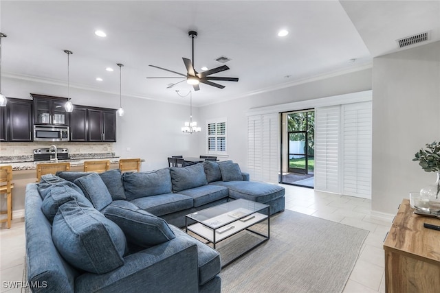 living room featuring sink, ceiling fan with notable chandelier, light tile patterned floors, and crown molding