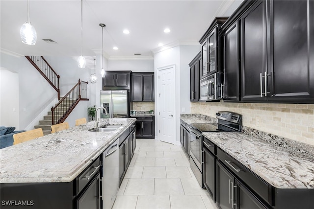 kitchen featuring stainless steel appliances, sink, backsplash, pendant lighting, and a large island with sink