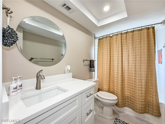 bathroom featuring tile patterned floors, vanity, a raised ceiling, and toilet