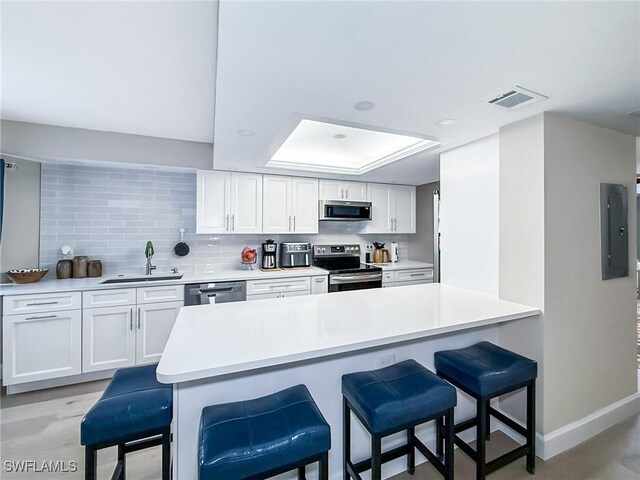 kitchen featuring a kitchen breakfast bar, white cabinetry, sink, and appliances with stainless steel finishes