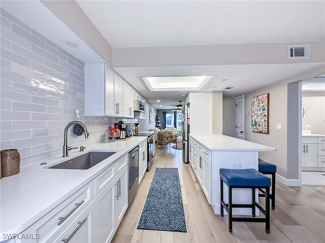 kitchen featuring white cabinetry, sink, light wood-type flooring, and appliances with stainless steel finishes