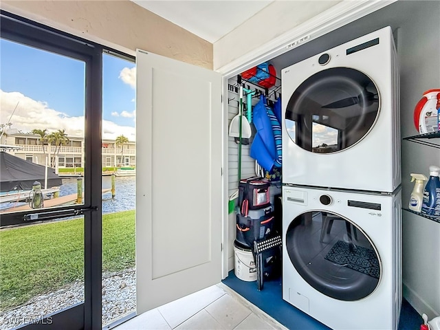 washroom featuring light tile patterned floors, stacked washer and dryer, and a water view