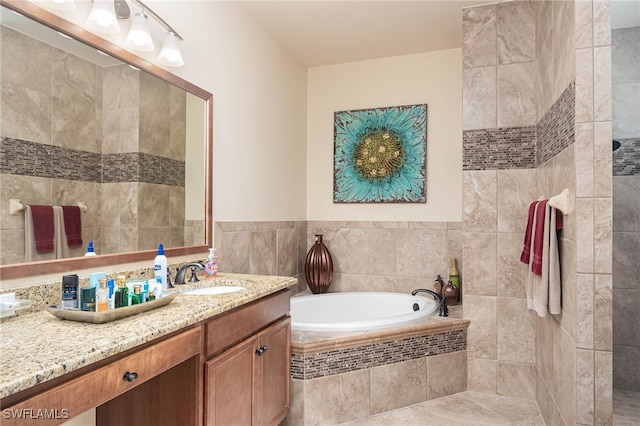 bathroom with vanity, tile walls, and tiled tub