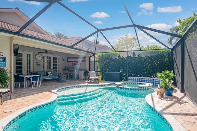 view of swimming pool with ceiling fan, a lanai, an in ground hot tub, a patio area, and exterior kitchen