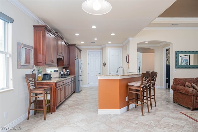 kitchen featuring a kitchen breakfast bar, a healthy amount of sunlight, and light stone countertops