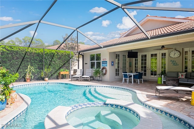 view of pool with glass enclosure, french doors, ceiling fan, an in ground hot tub, and a patio area