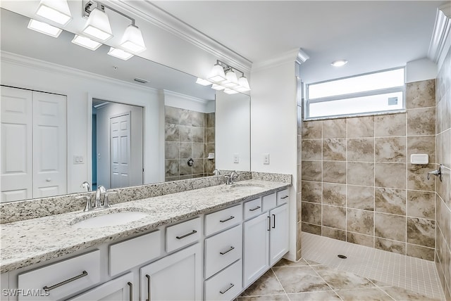 bathroom with tile patterned floors, vanity, a tile shower, and crown molding