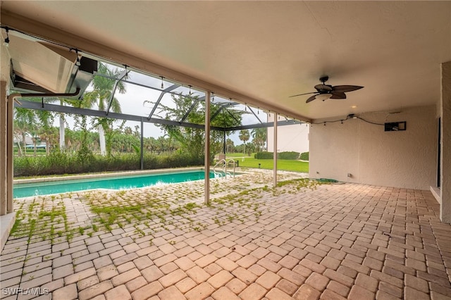 view of pool featuring glass enclosure, a patio area, and ceiling fan