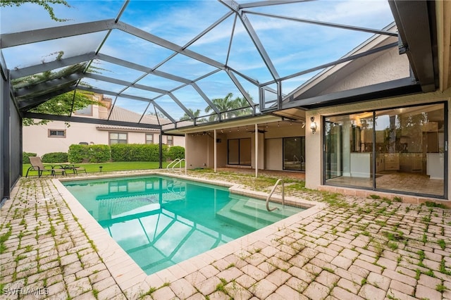 view of pool with ceiling fan, glass enclosure, and a patio area