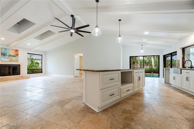 kitchen with vaulted ceiling with beams, white cabinetry, hanging light fixtures, ceiling fan, and a center island