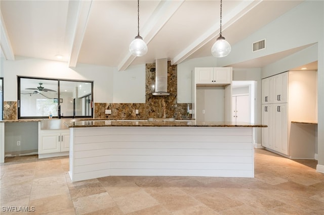 kitchen with white cabinetry, dark stone counters, and wall chimney range hood