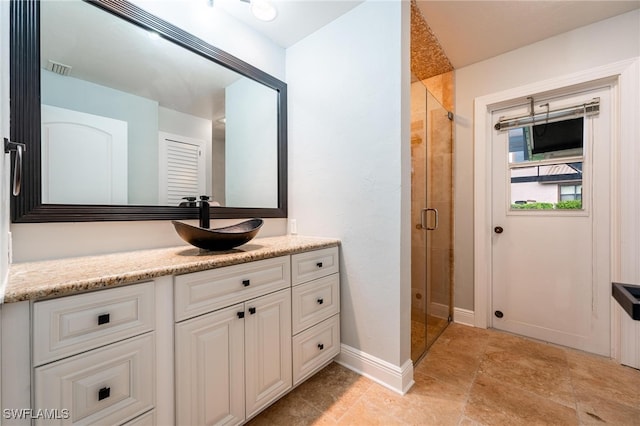 bathroom featuring a shower with door and vanity