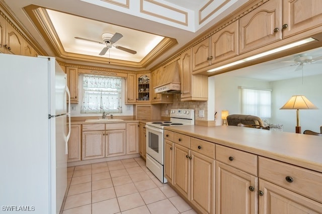 kitchen with a tray ceiling, custom range hood, a healthy amount of sunlight, and white appliances