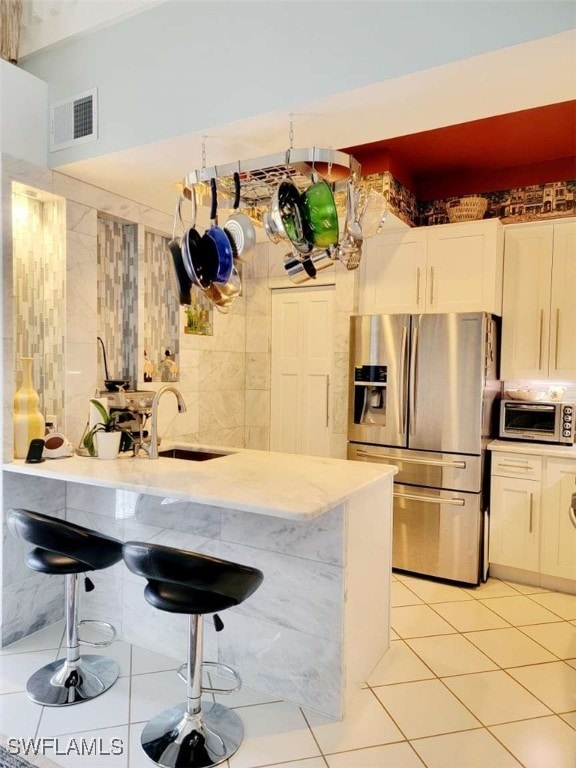 kitchen with a kitchen breakfast bar, white cabinetry, sink, and appliances with stainless steel finishes