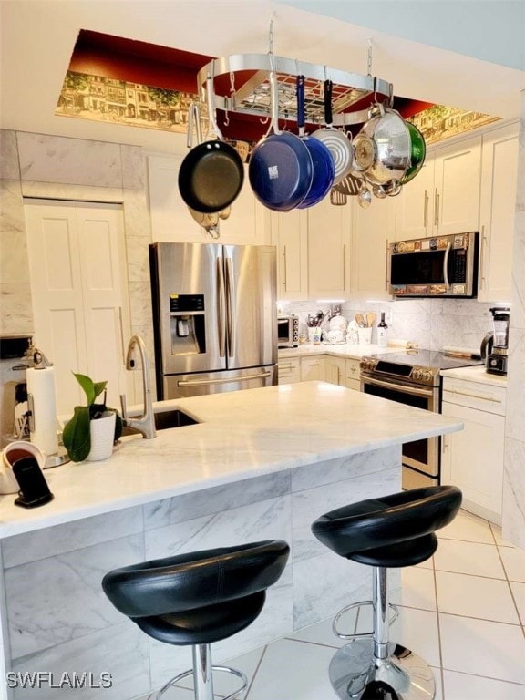 kitchen with a breakfast bar, sink, appliances with stainless steel finishes, and light stone countertops