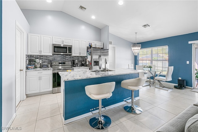 kitchen featuring decorative light fixtures, white cabinetry, lofted ceiling, and appliances with stainless steel finishes