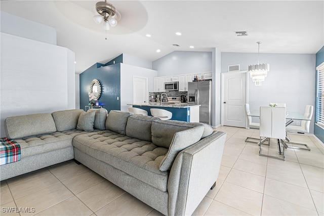 tiled living room with lofted ceiling, sink, and ceiling fan with notable chandelier