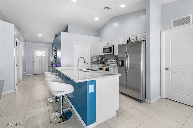 kitchen with white cabinets, a center island with sink, sink, light stone countertops, and stainless steel appliances