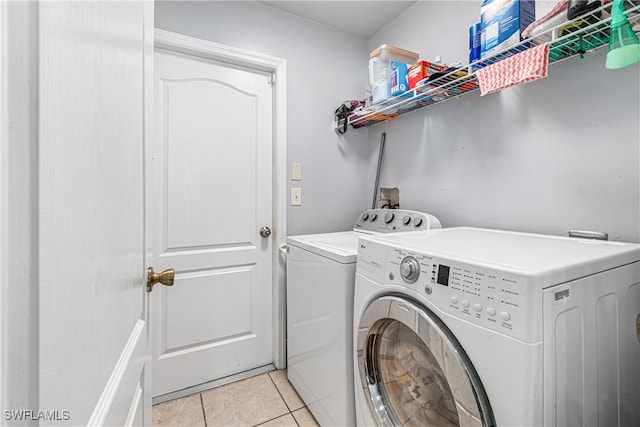 clothes washing area with light tile patterned floors and separate washer and dryer