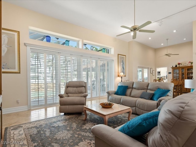 living room with ceiling fan, a healthy amount of sunlight, and a towering ceiling