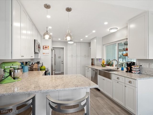 kitchen featuring a kitchen bar, kitchen peninsula, appliances with stainless steel finishes, and white cabinets