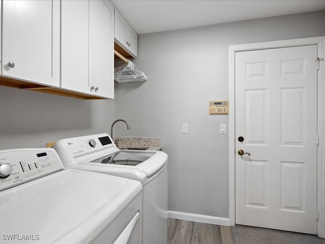 washroom with washer and clothes dryer, light wood-type flooring, cabinets, and sink