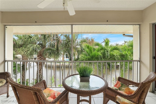 sunroom / solarium featuring ceiling fan and a water view